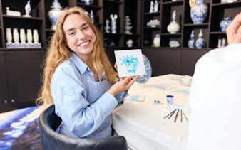 Guest displaying painted tile at Dutch Blue Tile Painting Workshop.