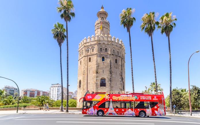 Hop-On-Hop-Off bus in front of Torre del Oro, Seville.