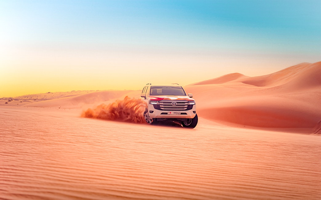 SUV driving through sand dunes during Abu Dhabi desert safari.