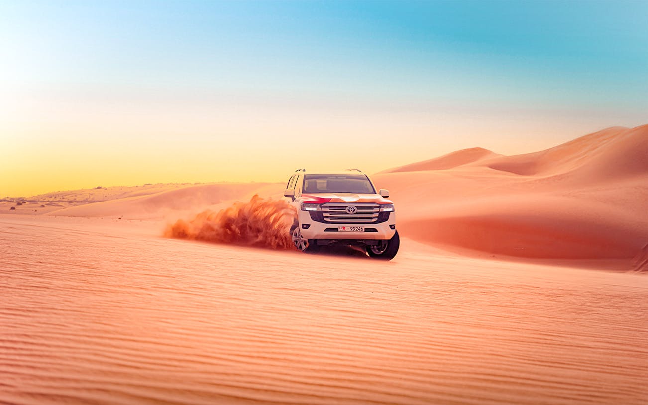 SUV driving through sand dunes during Abu Dhabi desert safari.