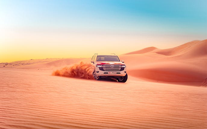 SUV driving through sand dunes during Abu Dhabi desert safari.