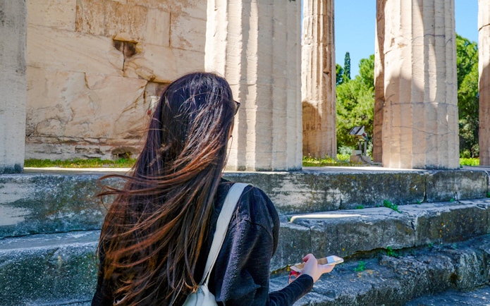 Woman using audio guide at Ancient Agora ruins in Athens.