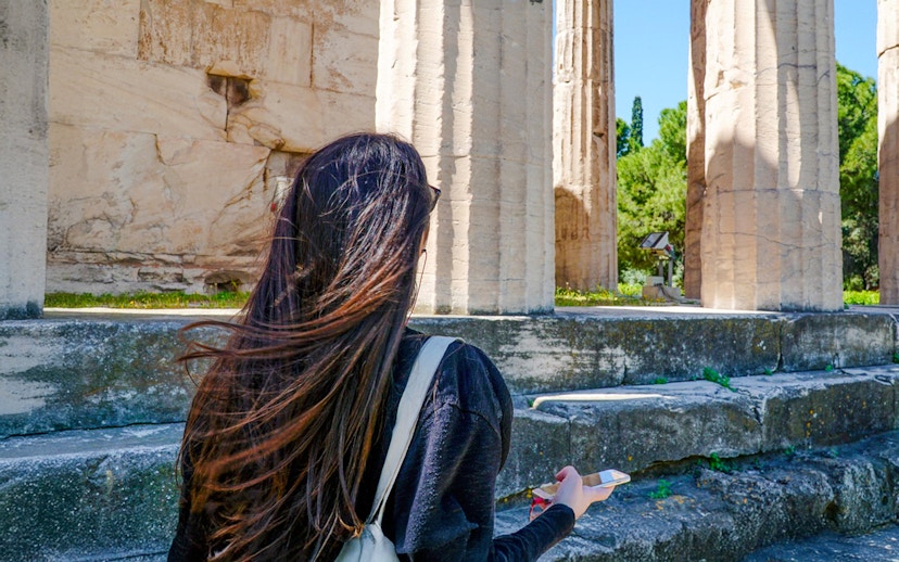 Woman using audio guide at Ancient Agora ruins in Athens.