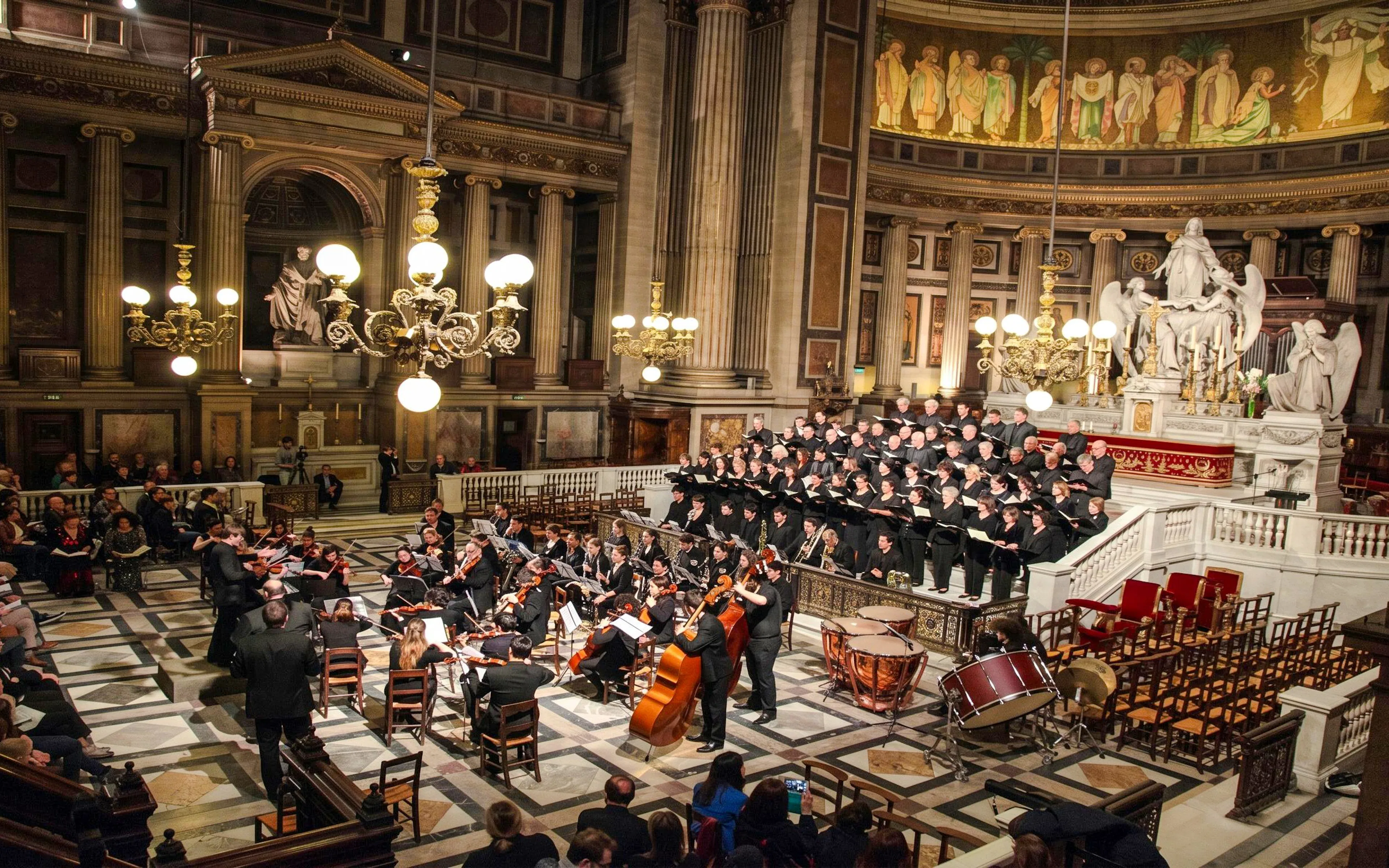Orchestra Hélios performing in Église de la Madeleine, Paris, with choir and audience.
