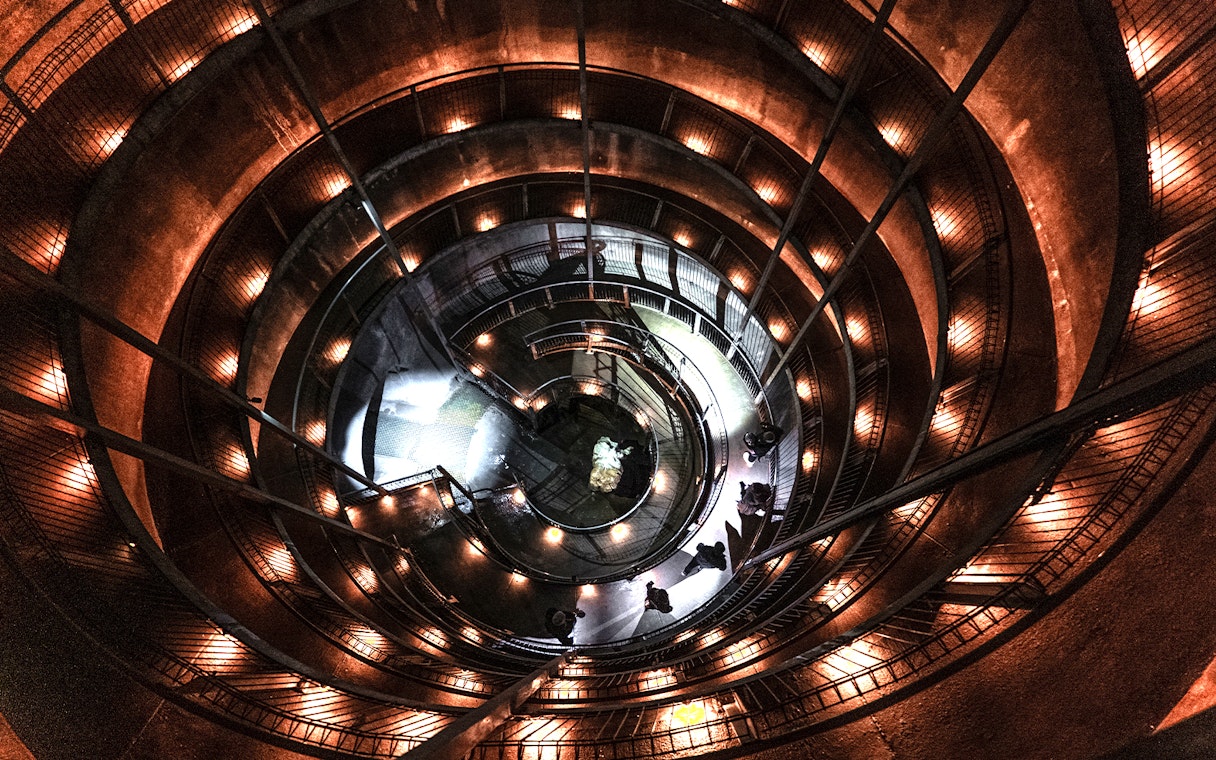 Spiral walkway inside Ruakuri Cave, New Zealand, illuminated with warm lights.
