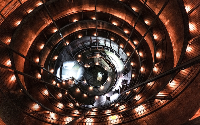 Spiral walkway inside Ruakuri Cave, New Zealand, illuminated with warm lights.