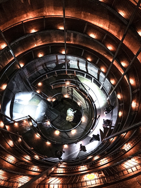 Spiral walkway inside Ruakuri Cave, New Zealand, illuminated with warm lights.