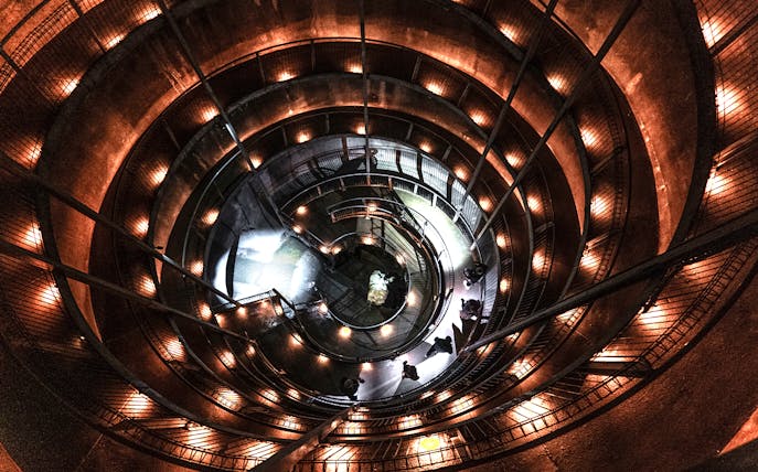 Spiral walkway inside Ruakuri Cave, New Zealand, illuminated with warm lights.