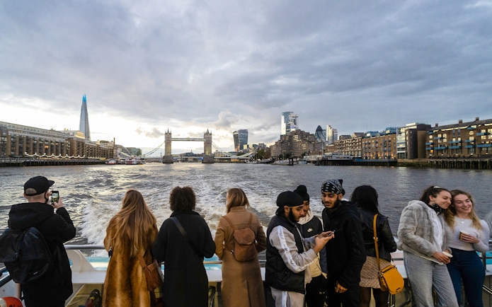 Passengers enjoying Thames River Uber Boat Tour with view of Tower Bridge and London skyline.