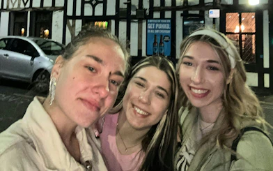 Three people smiling outside a pub in Manchester during a city exploration game.