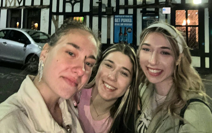 Three people smiling outside a pub in Manchester during a city exploration game.