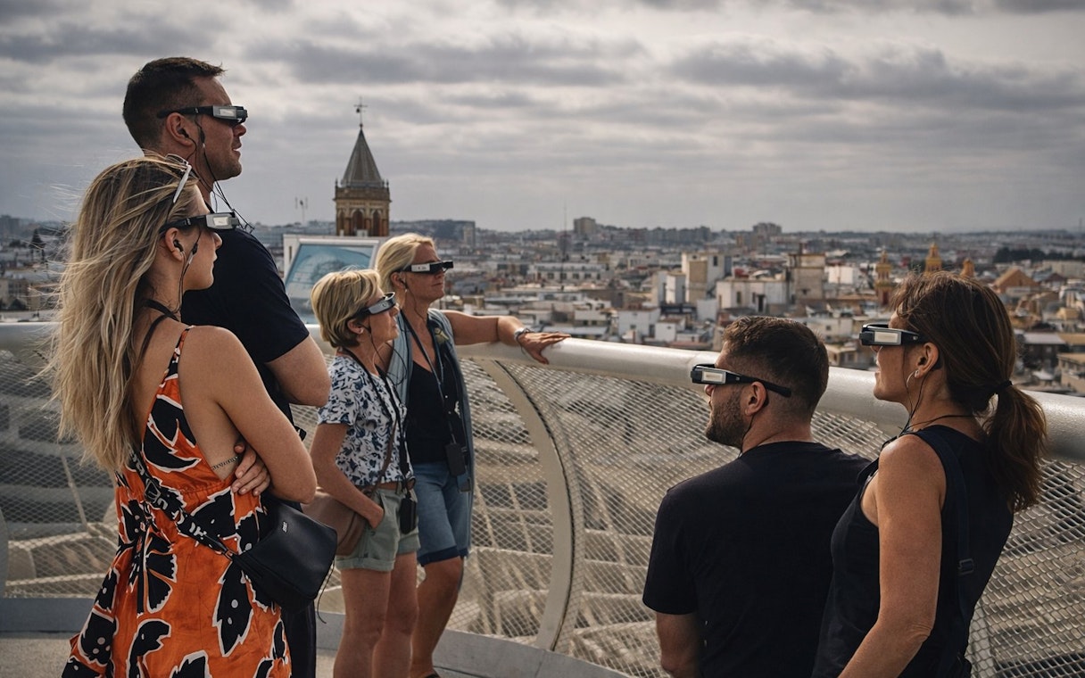 Tourists wearing smart glasses during a guided tour at Setas de Sevilla, overlooking the city.