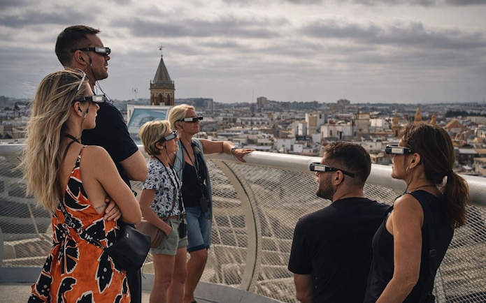 Tourists wearing smart glasses during a guided tour at Setas de Sevilla, overlooking the city.