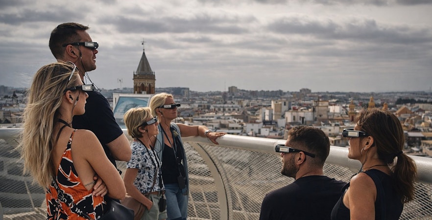 Tourists wearing smart glasses during a guided tour at Setas de Sevilla, overlooking the city.