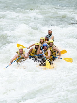 Group whitewater rafting on Tully River, navigating rapids with paddles.