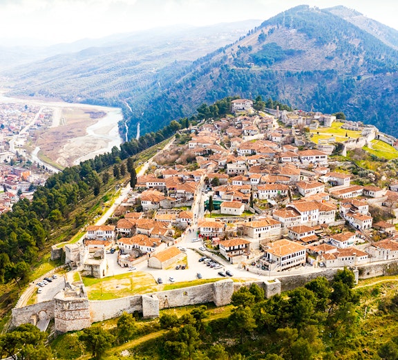 Aerial view of Berat, Albania, showcasing castle walls and tiled roofs.