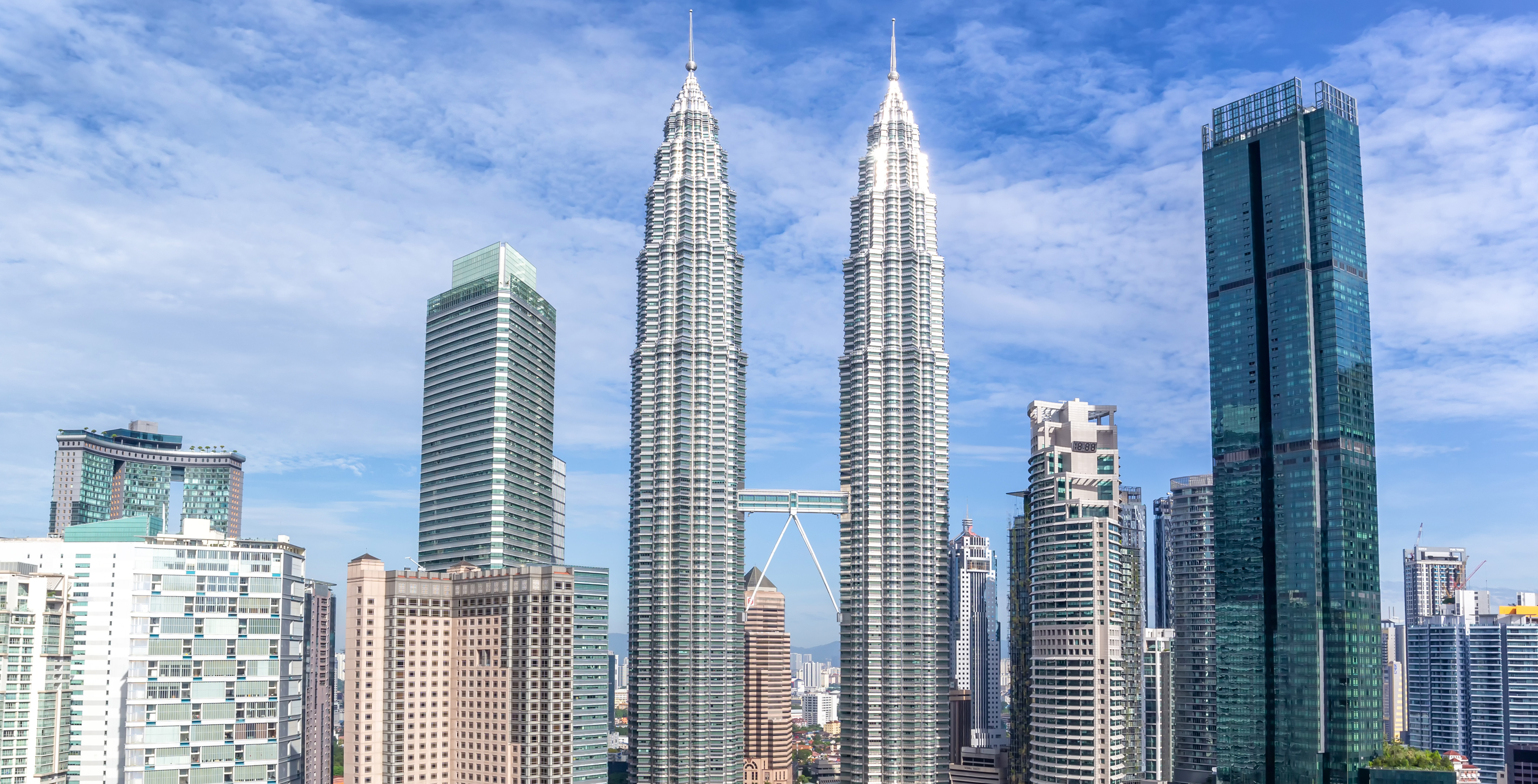 Petronas Twin Towers in Kuala Lumpur illuminated at night with city skyline in the background.