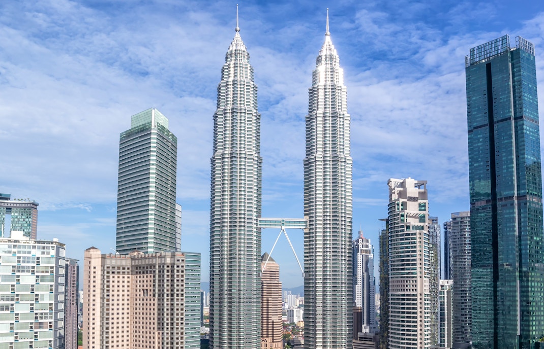 Petronas Twin Towers in Kuala Lumpur illuminated at night with city skyline in the background.