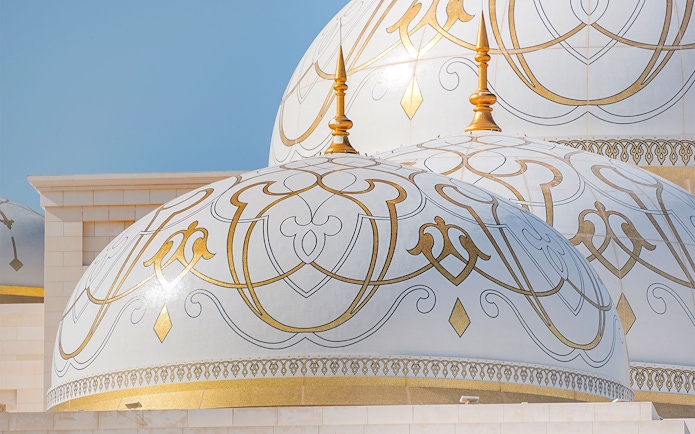 Ornate domes of Qasr Al Watan in Abu Dhabi with intricate gold patterns.