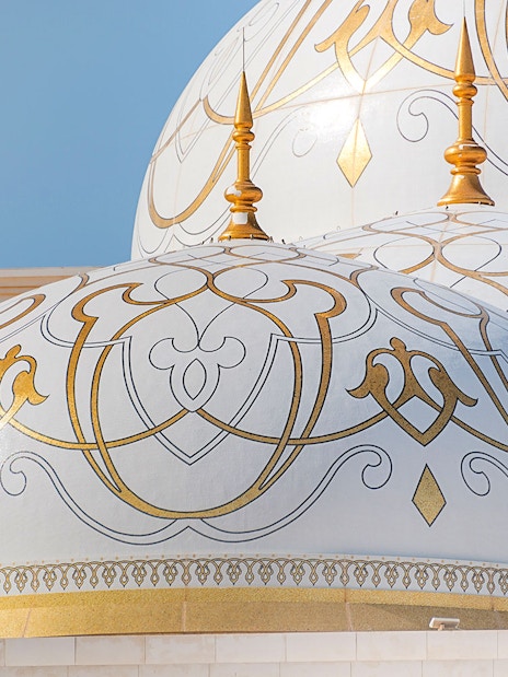 Ornate domes of Qasr Al Watan in Abu Dhabi with intricate gold patterns.