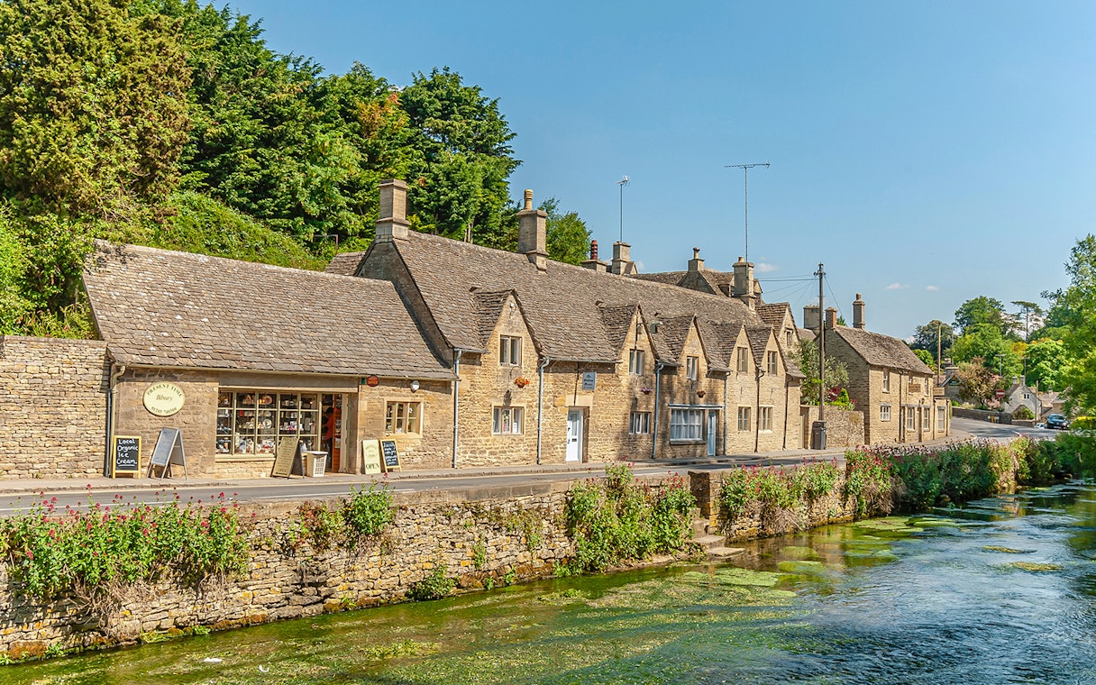 Cotswolds village street with stone cottages and a stream, part of Blenheim Palace and Downton Abbey tour.