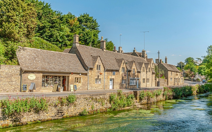 Cotswolds village street with stone cottages and a stream, part of Blenheim Palace and Downton Abbey tour.