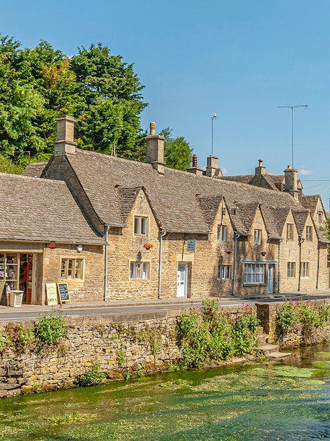 Cotswolds village street with stone cottages and a stream, part of Blenheim Palace and Downton Abbey tour.