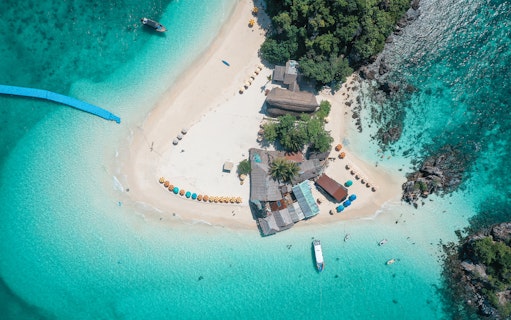 Aerial view of Khai Island beach with colorful umbrellas and speedboat in turquoise water, Phuket tour.