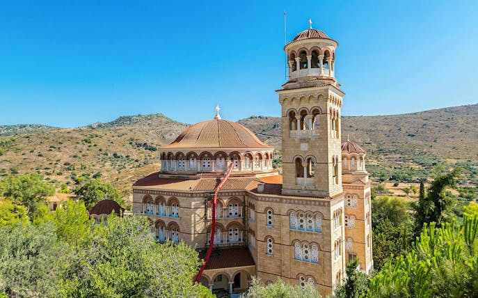 Saint Nektarios church with bell tower on Aegina island, Greece, surrounded by hills.