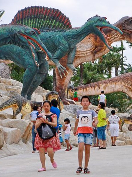 Visitors walking among dinosaur sculptures at Nong Nooch Tropical Garden, Thailand.