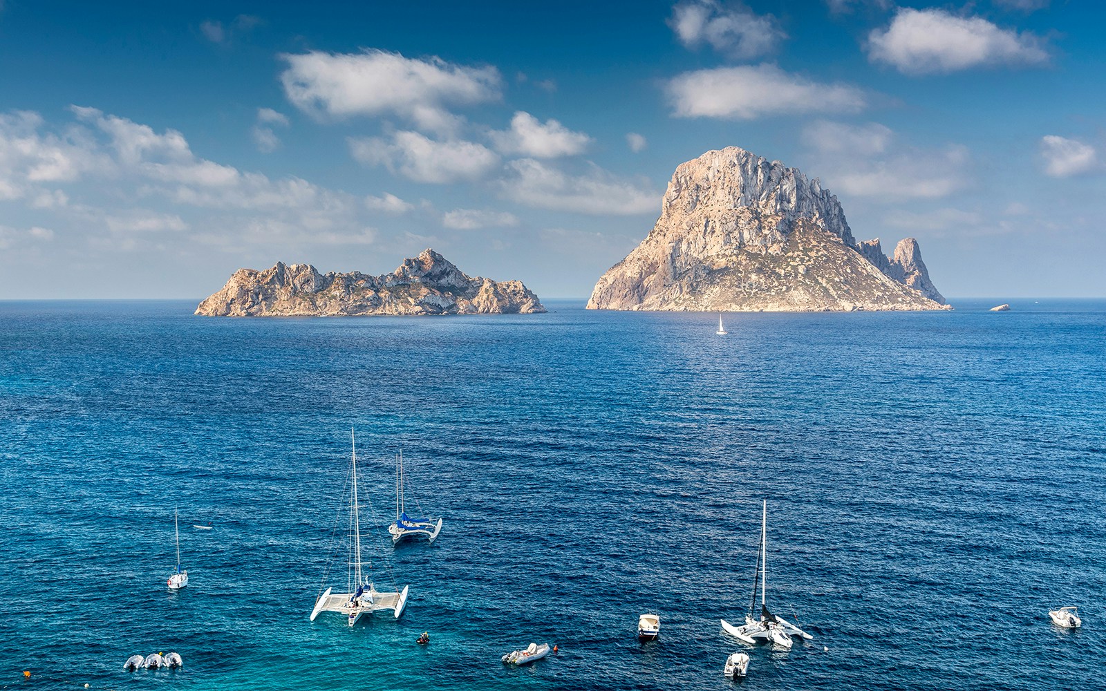 Seawater of Es Vedrà with a few ships sailing during daytime