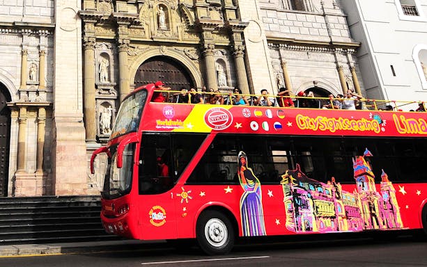 Double-decker bus in Lima, Peru, passing by historic colonial architecture on a city tour.