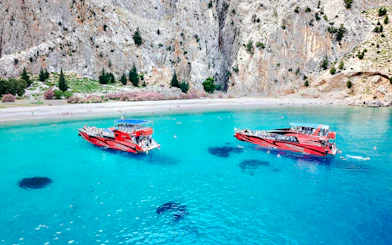 High-speed cruise boats on turquoise waters near rocky cliffs in Rhodes.