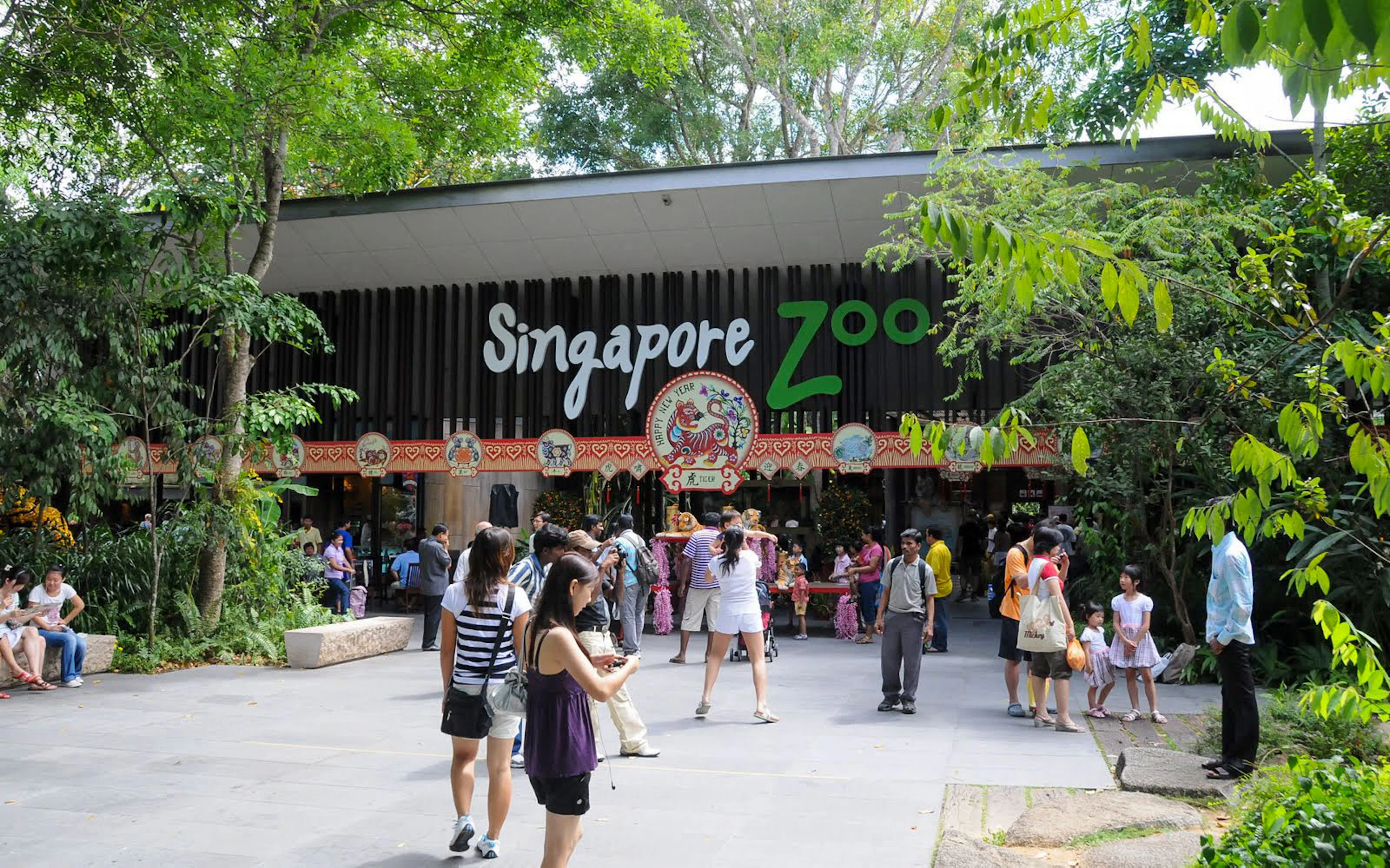 Visitors at the entrance of Singapore Zoo surrounded by lush greenery.