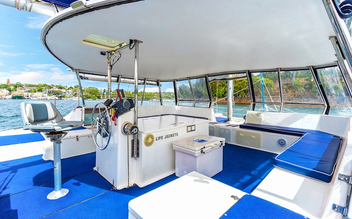 Catamaran interior with seating and steering wheel on Vivid Sydney BYO Kirralee Cruise.