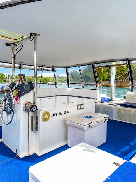 Catamaran interior with seating and steering wheel on Vivid Sydney BYO Kirralee Cruise.