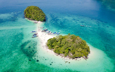 Aerial view of Krabi's 4 Islands with longtail boats and tourists on sandy beach.