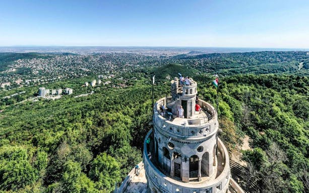 Aerial view of Janos Hill Lookout Tower surrounded by lush greenery in Budapest, Hungary.