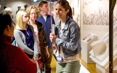 Guide engaging with tour group at Statue of Liberty exhibit.