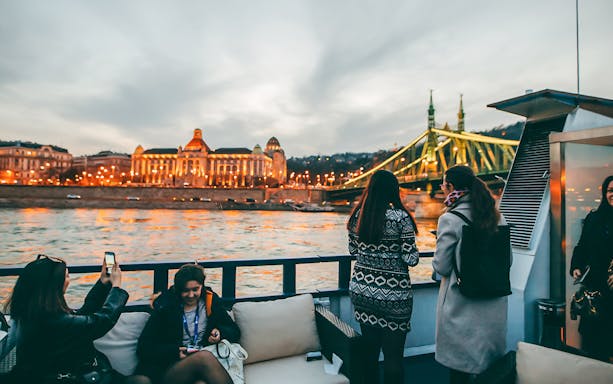 Guests on a New Year's Eve dinner cruise enjoying views of Budapest's Liberty Bridge and Gellért Hotel.