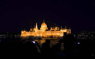 Hungarian Parliament Building illuminated at night from Danube River cruise in Budapest.