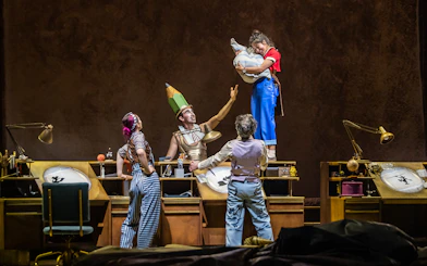 Performers in colorful costumes interact on stage during the "Drawn to Life" show.