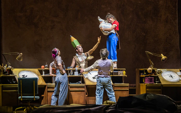 Performers in colorful costumes interact on stage during the "Drawn to Life" show.