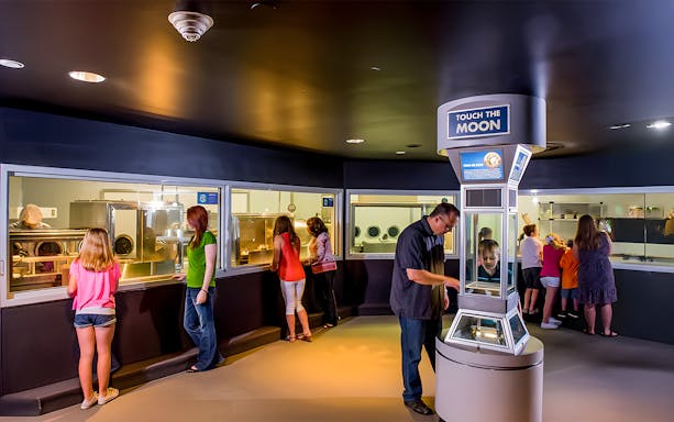 Visitors exploring exhibits at Houston Space Center, including space artifacts and interactive displays.