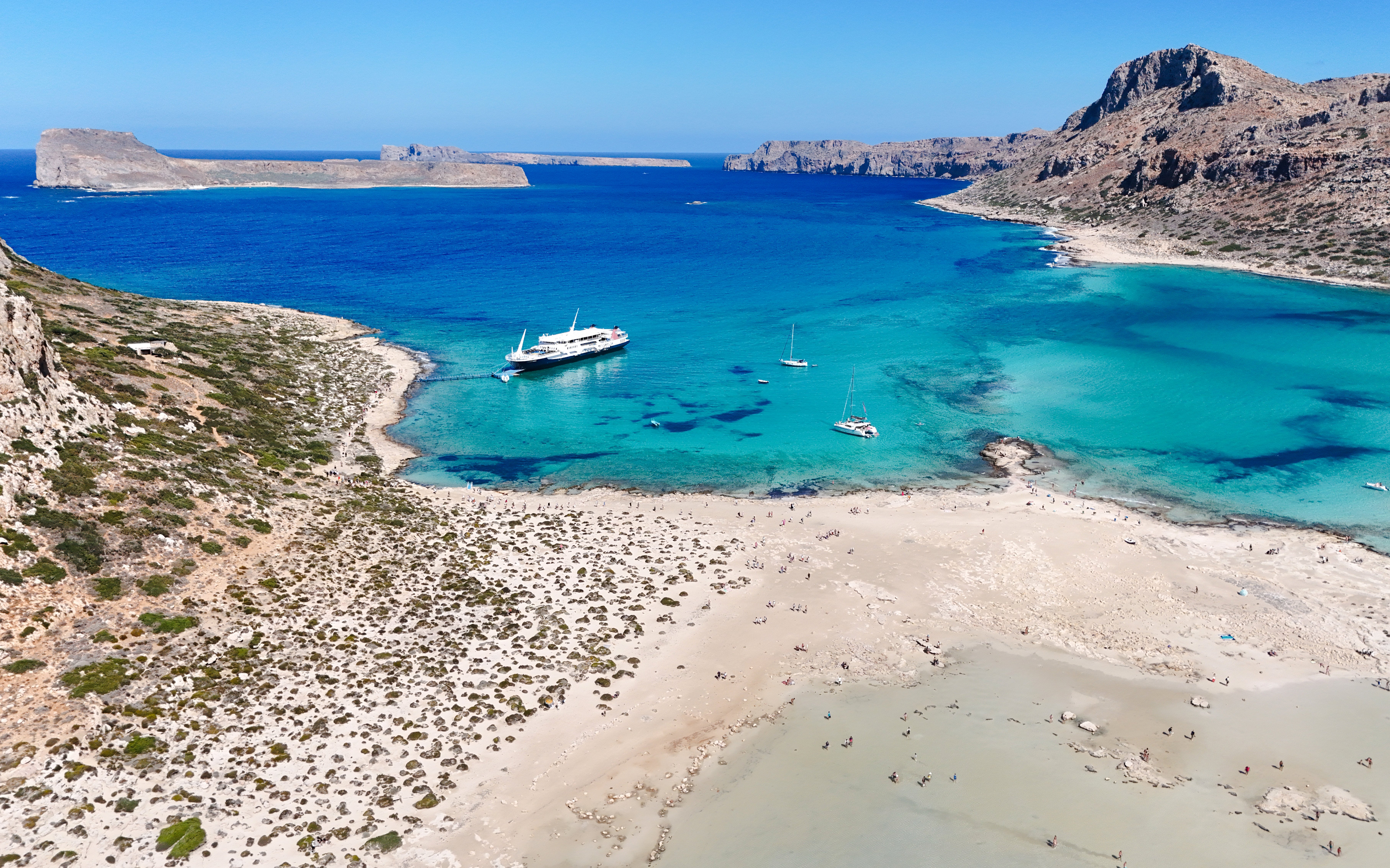 Boat cruise approaching Balos Lagoon, Crete, with turquoise waters and sandy beach.