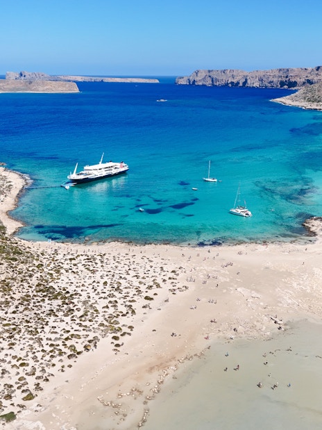 Boat cruise approaching Balos Lagoon, Crete, with turquoise waters and sandy beach.