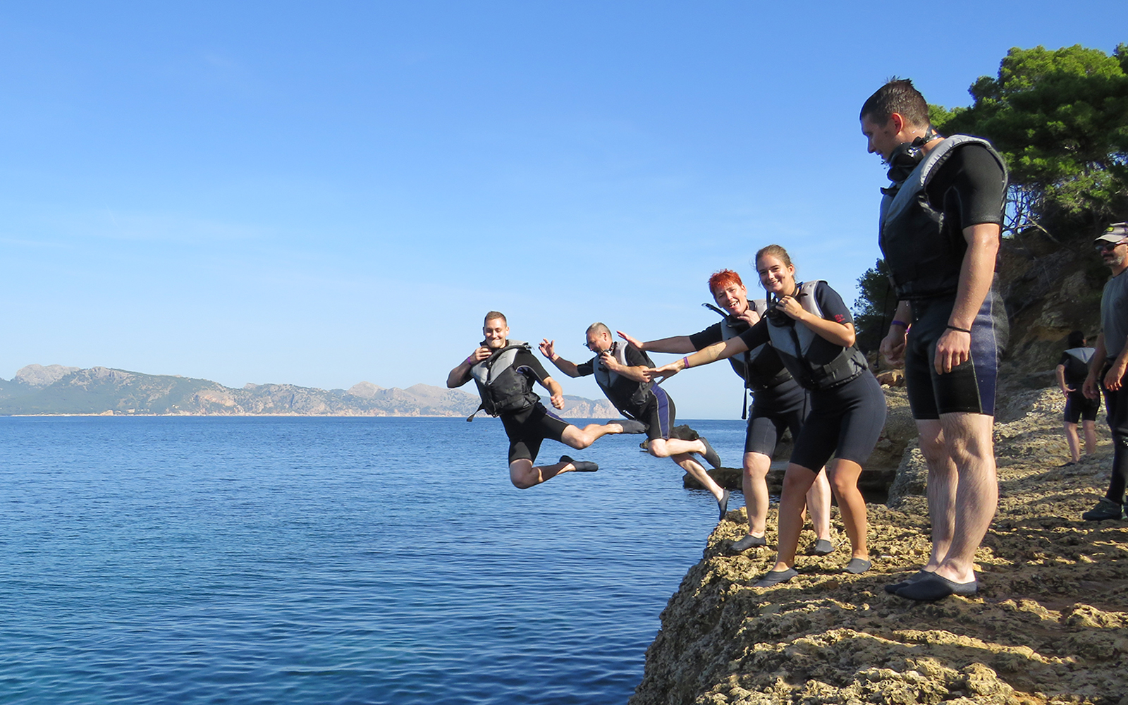 Group cliff jumping into the sea in Mallorca during an outdoor adventure tour.