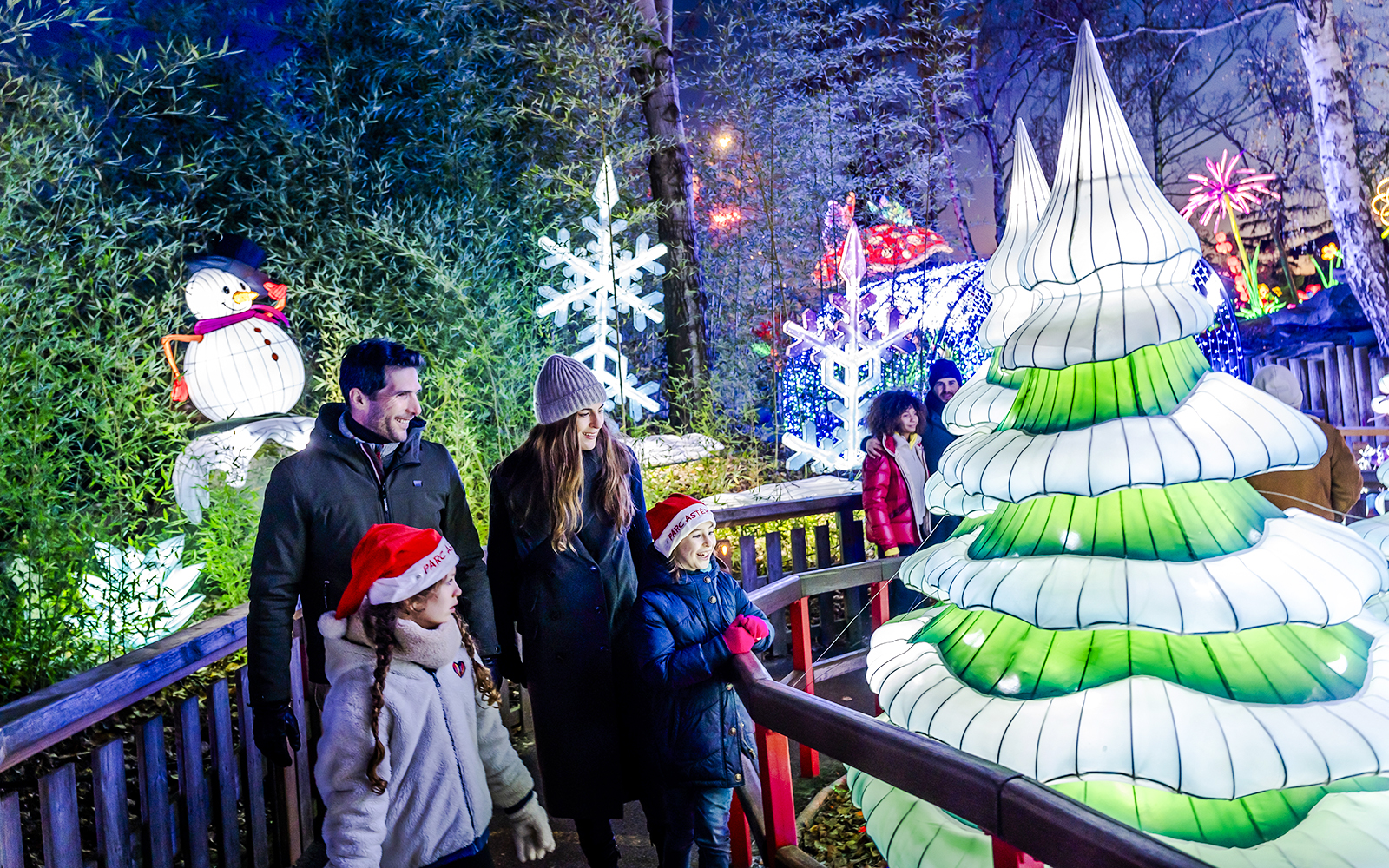 Family enjoying Christmas lights at Parc Asterix with snowman and festive decorations.