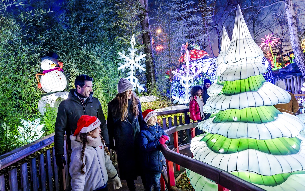 Family enjoying Christmas lights at Parc Asterix with snowman and festive decorations.