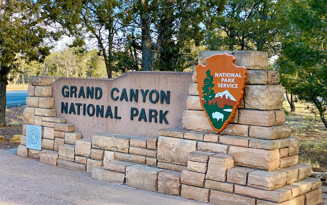 Grand Canyon National Park entrance sign with National Park Service emblem.